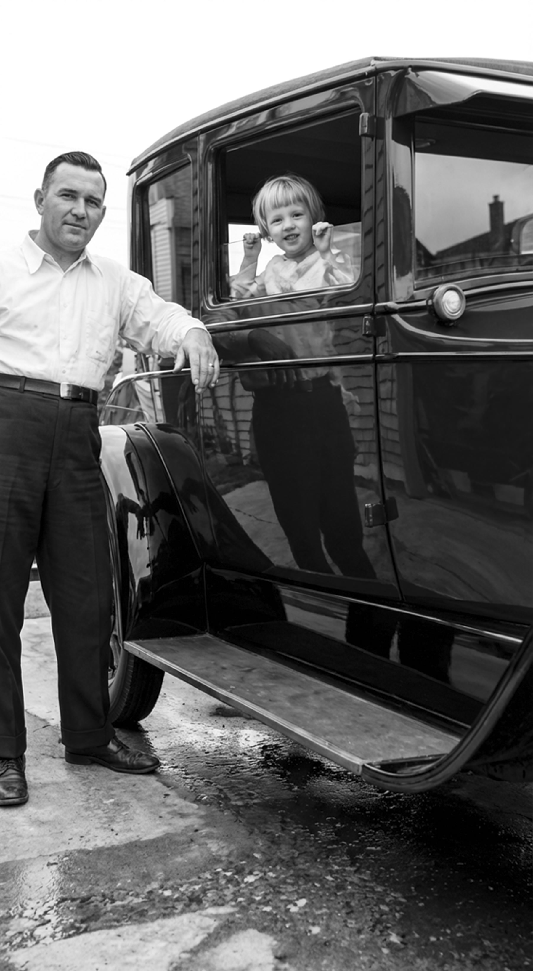 A detailed black-and-white reconstruction of the father and smiling child beside the vintage car